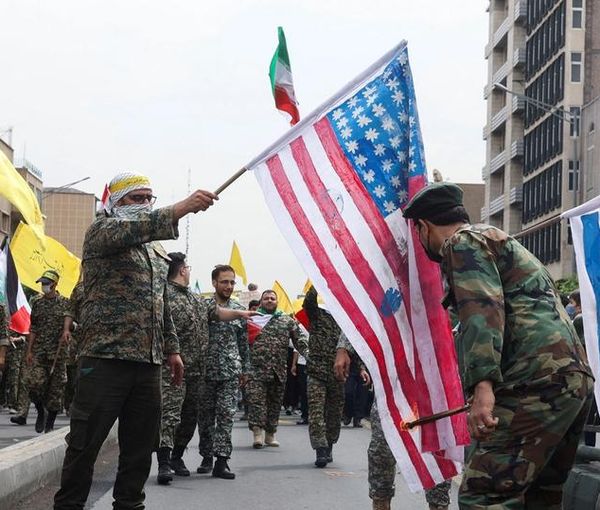 Men in military uniforms setting fire to Israeli and US flags during Quds day rallies in Tehran on April 29, 2022