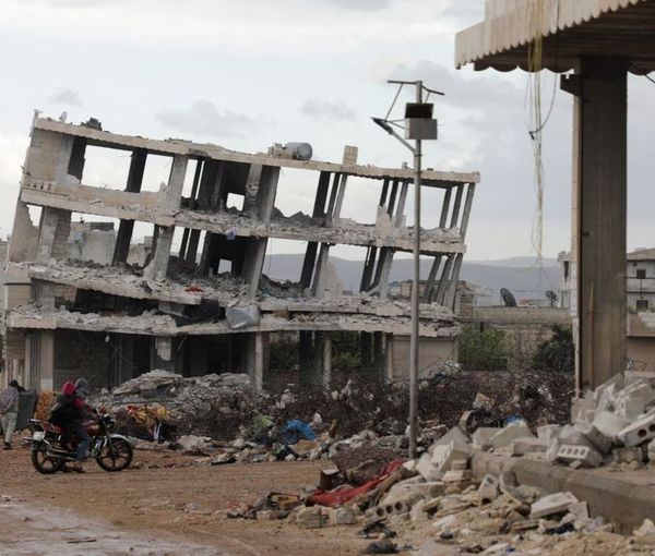 People ride a motorbike past buildings damaged by an earthquake that hit Syria on February 6, in the rebel-held town of Jandaris, Syria March 29, 2023.