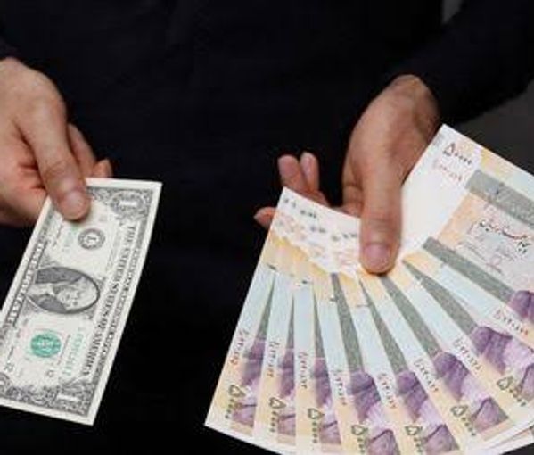 A currency dealer poses for a photo with a U.S one dollar bill and the amount being given when converting it into Iranian rials in an exchange shop in Tehran, Iran December 25, 2022.