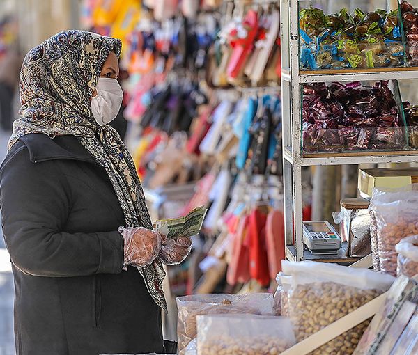 A woman shopping in Tehran with Iranian currency in hand. Undated