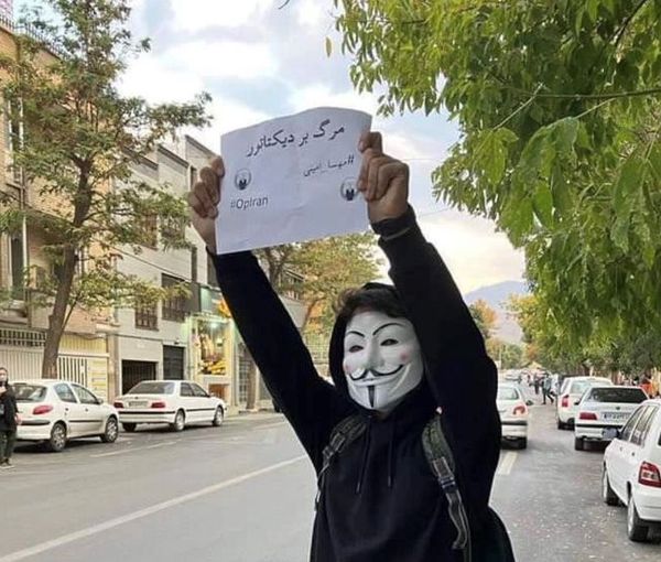 A protester in Tehran holding up a sign that says, "Death to the dictator". October 2022