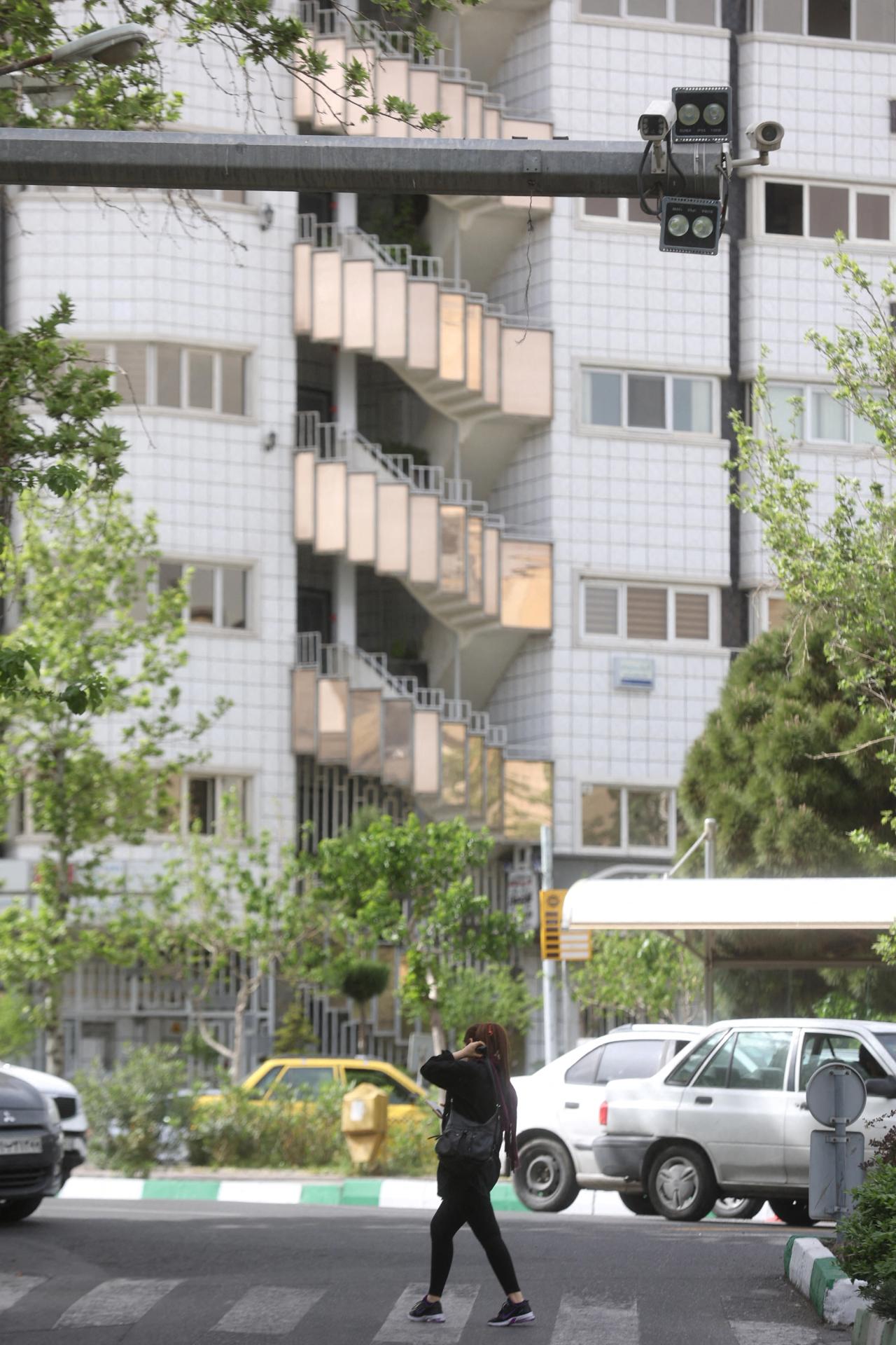 An Iranian woman walks without hijab under a surveillance camera in Tehran