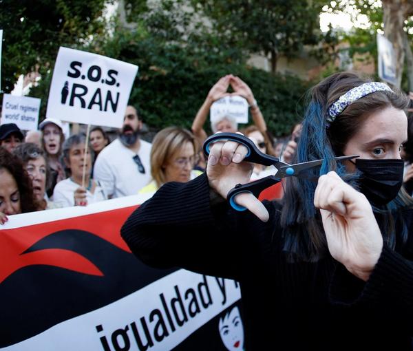 A woman cuts her hair during a protest against the Islamic regime of Iran and the death of Mahsa Amini in front of the Iranian Embassy in Madrid, Spain October 6, 2022.