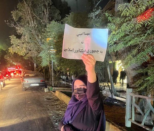 A lone woman in the street holding a sign that says, "NO to the dictatorial Islamic Republic. October 2022