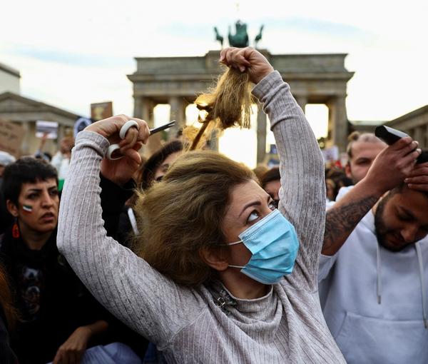 A demonstrator cuts hair during a protest following the death of Mahsa Amini, in front of the Brandenburg Gate in Berlin, September 23, 2022