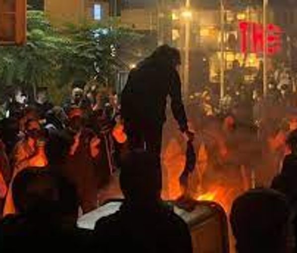 An undated photo showing protesters lighting a fire in the street and burning veils