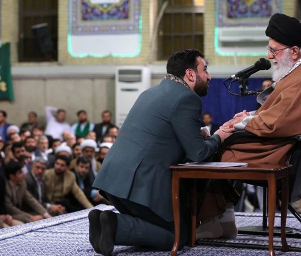 Khamenei seen with a religious singer kneeling in front of him. Undated