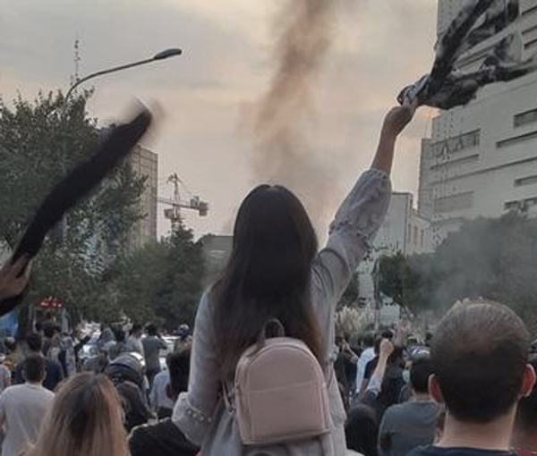 A woman taking off her headscarf during a protest in Iran. September 2022