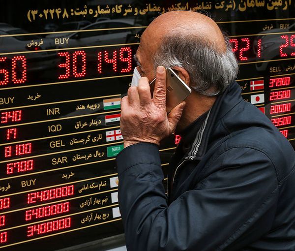 File photo of an Iranian man passing in front of a board that shows exchange rates against rial (file photo)