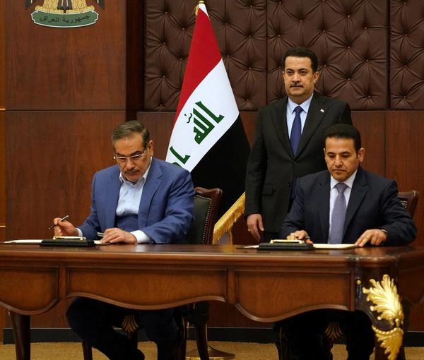 Iraqi Prime Minister Mohammed Shia al-Sudani looks on as Iraq's National Security Adviser Qasim al-Araji and Iran's Supreme National Security Council secretary Ali Shamkhani sign a security agreement, in Baghdad, March 19, 2023