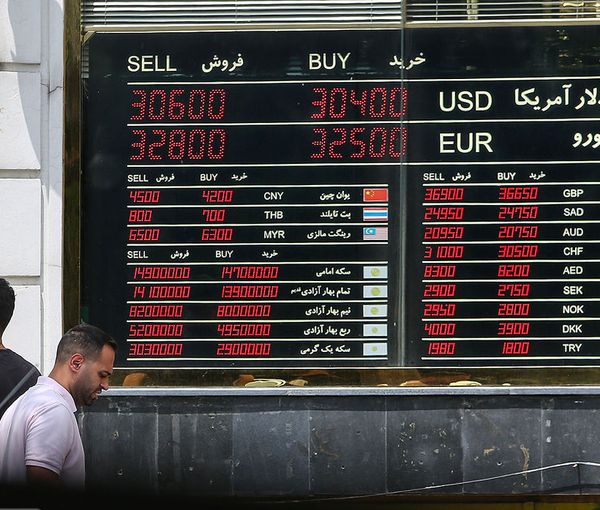 File photo of people in front of a board that shows exchange rates against rial 
