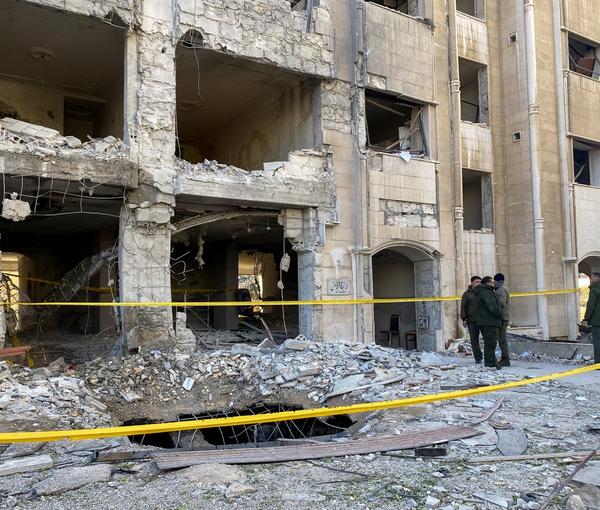 Police officers stand near a damaged building at the site of a rocket attack in the Kafr Sousa neighbourhood of central Damascus, Syria, February 19, 2023.