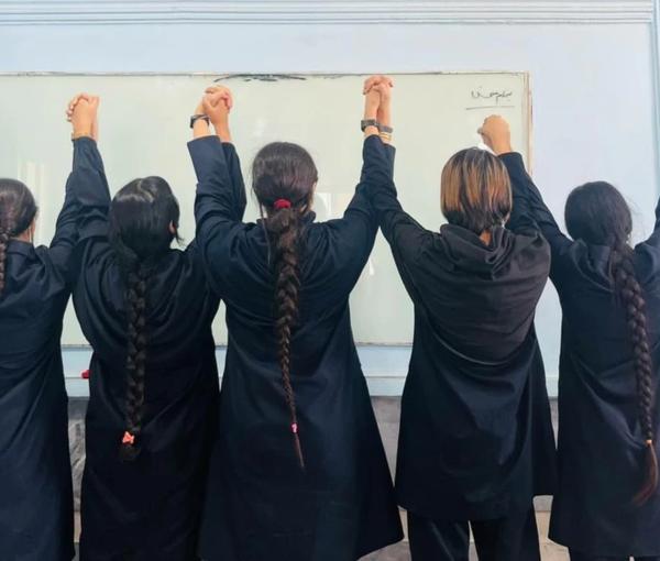 A number of schoolgirls removing their headscarves in support of the protests
