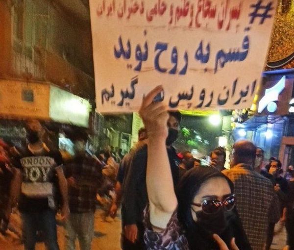 A woman with headscarf in Tehran vows to continue protests carrying a placard that says, "We will take back Iran". Oct. 15, 2022