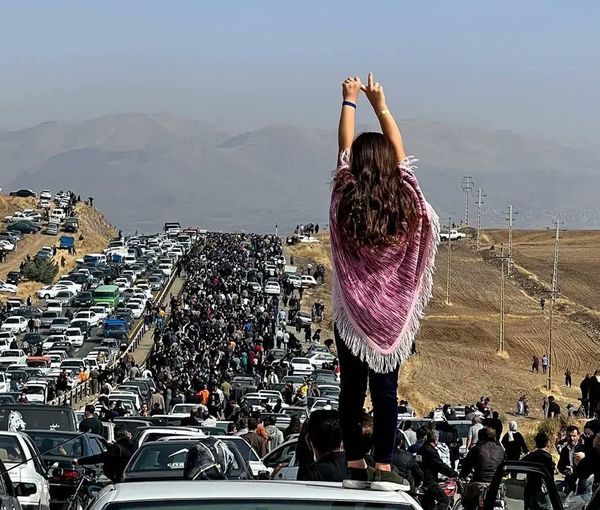 A woman standing on top of a vehicle as thousands make their way towards the cemetery in Saqqez, Mahsa Amini’s hometown in the western Iranian province of Kordestan, to mark the 40th day since her death 