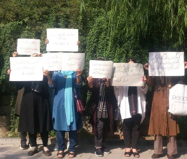 A woman seen in a Tehran street holding placards in protest, August 15, 2022
