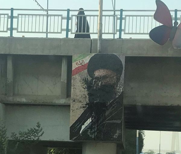 A large poster of Supreme Leader Ali Khamenei splashed with black paint in Tehran in October 2022