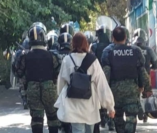 A woman walking without a hijab next to police officers, October 3, 2022