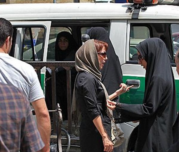 A woman with a headscarf showing part of hair being questioned by 'chastity police' in Iran equipeed with a special van to detain women. June 2022