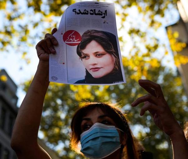 A young woman holding up the picture of Mahsa Amini in Tehran