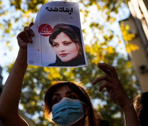 A woman protester in Iran holding a picture of Mahsa Amini who was killed in hijab police custody. Undated