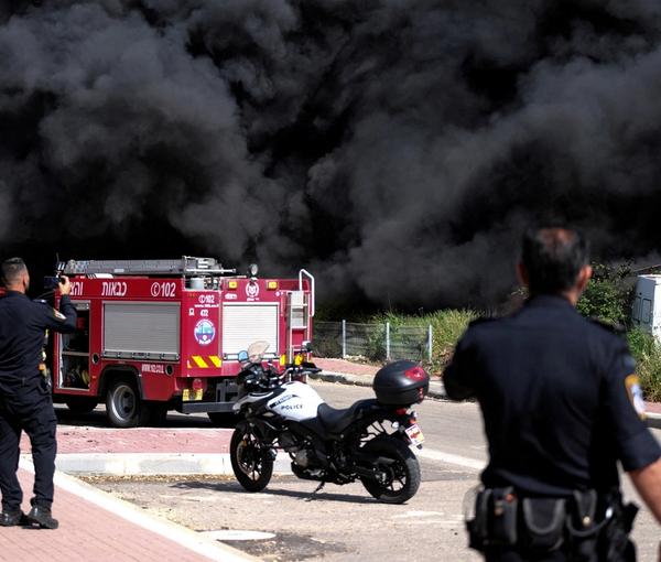Israeli policemen stand next to smoke from a fire following incoming rockets from Lebanon to Israel in Bezet, northern Israel April 6, 2023
