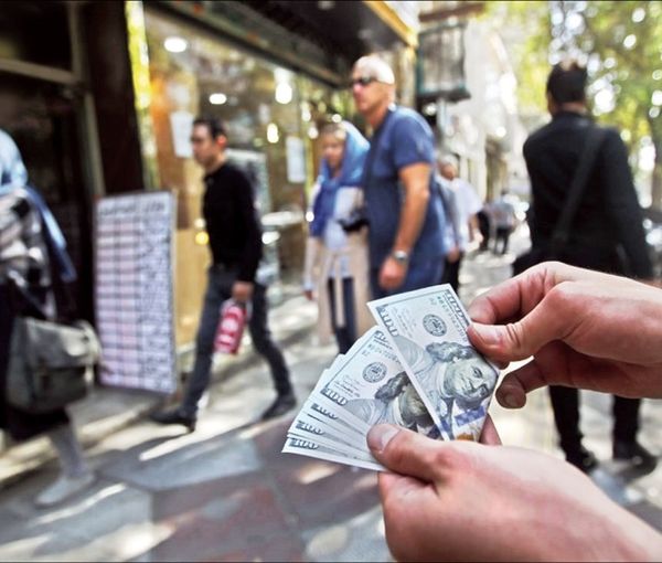 A man holding US dollar notes in a Tehran street outside a currency exchange. Undated