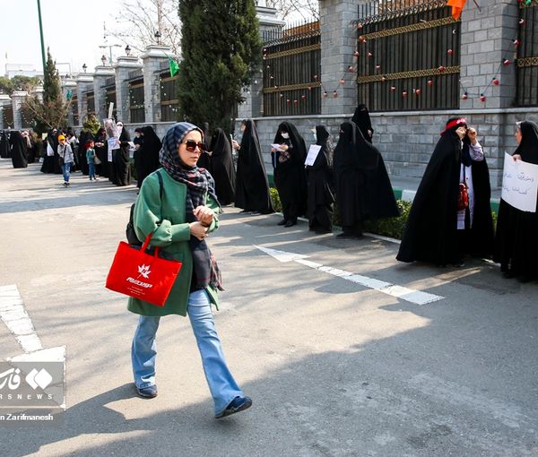 An Iranian woman walking in front of regime-sponsored pro-hijab protesters (undated)